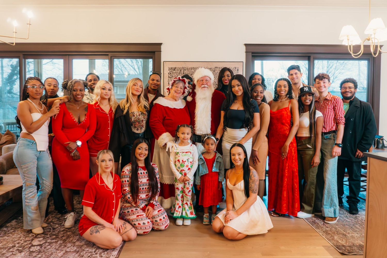 A group of people dressed in red and other colors pose together for a formal gathering photo in an indoor setting.