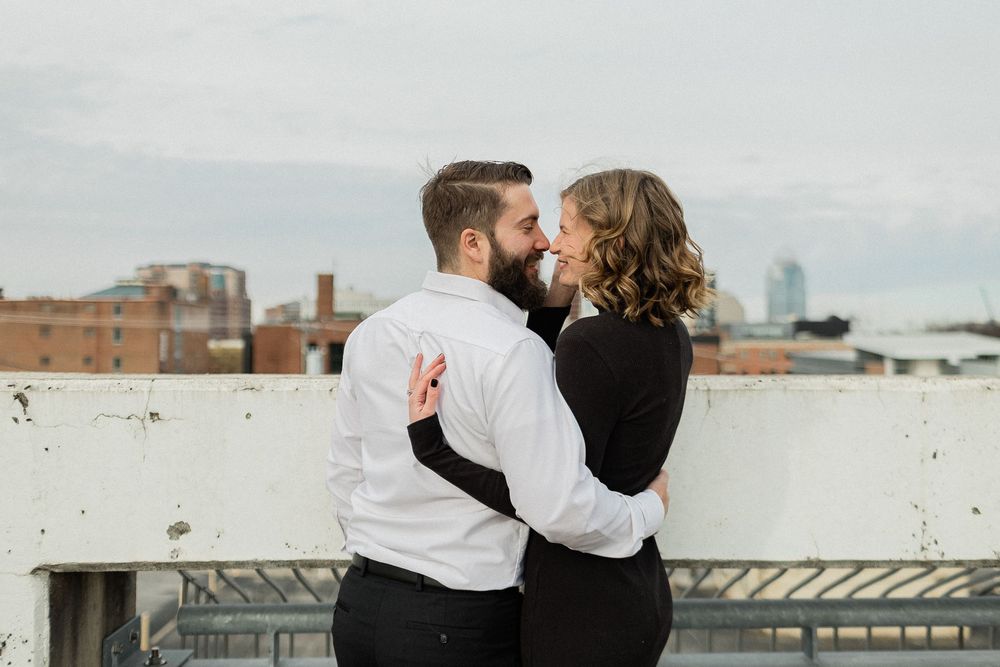 A romantic couple shares tender moments on a rooftop overlooking a city skyline.