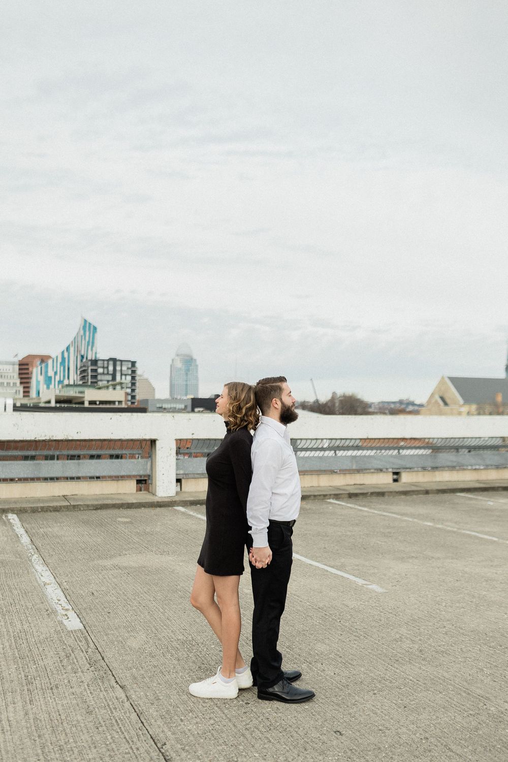 Two people in black and white outfits walk together across a minimalist concrete rooftop space.