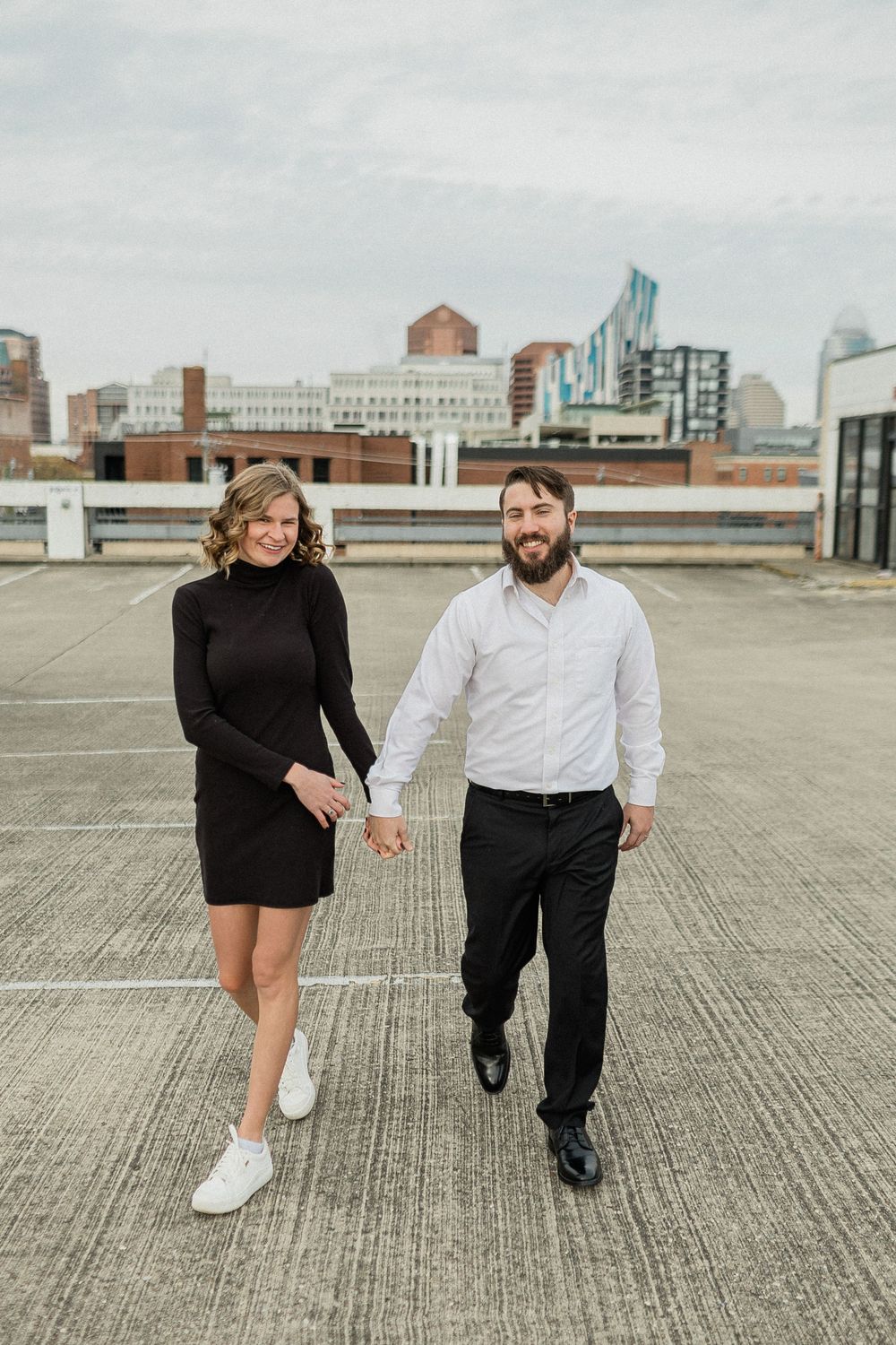 A couple dances together on a concrete rooftop with an urban skyline visible behind them.