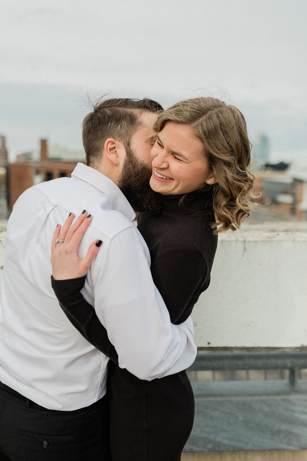 A couple embraces and laughs together on an urban rooftop in a romantic photoshoot series.