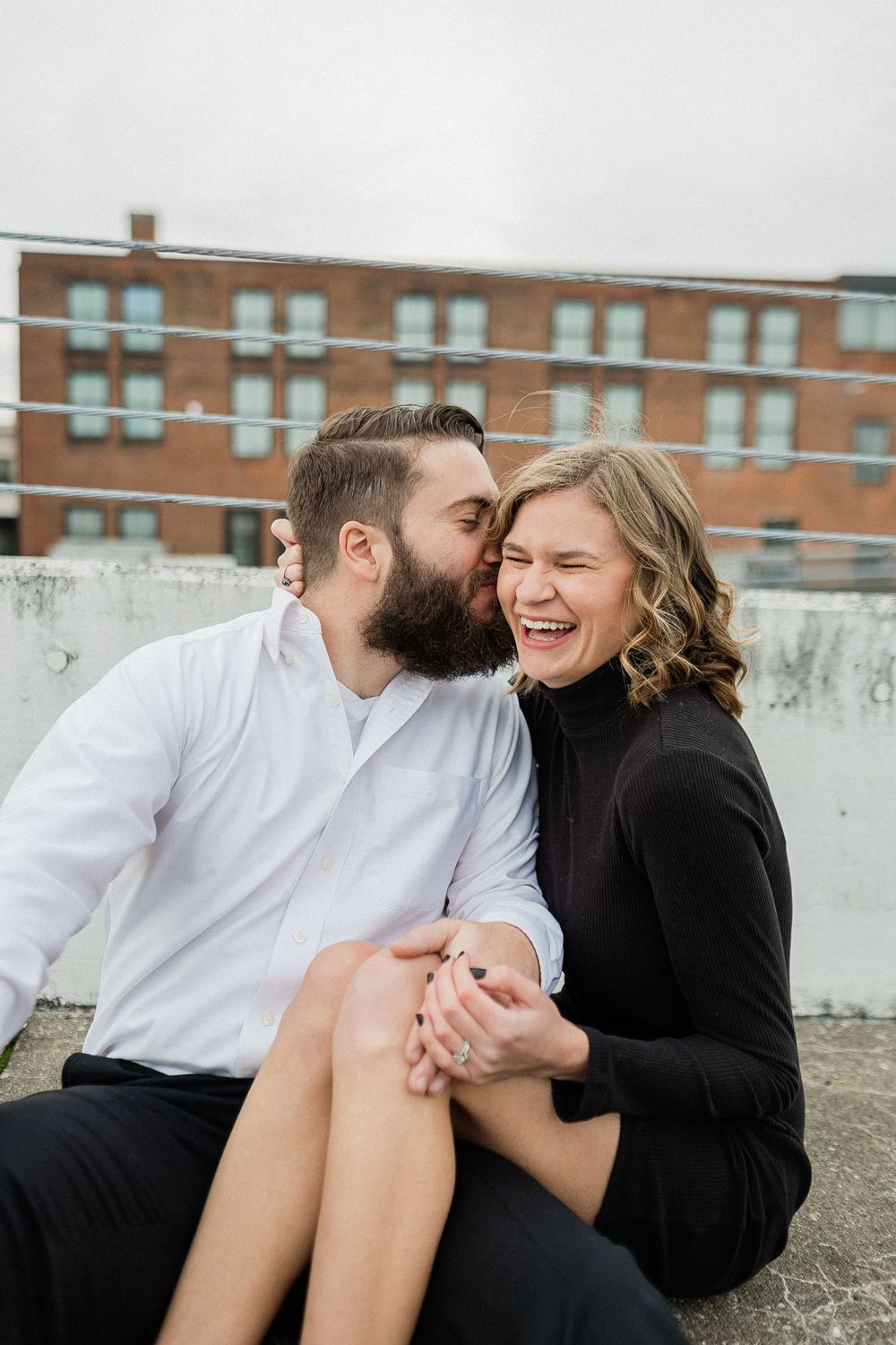 A romantic moment shared between a couple laughing and embracing on an urban rooftop.