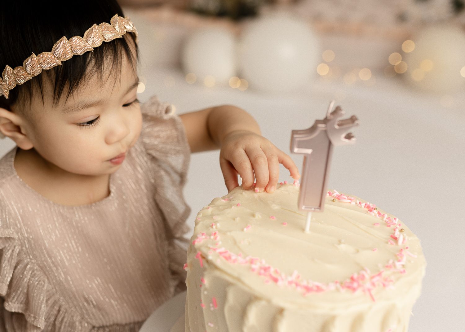 A child blows out a candle on a white birthday cake decorated with pink sprinkles in a series of sequential photos.