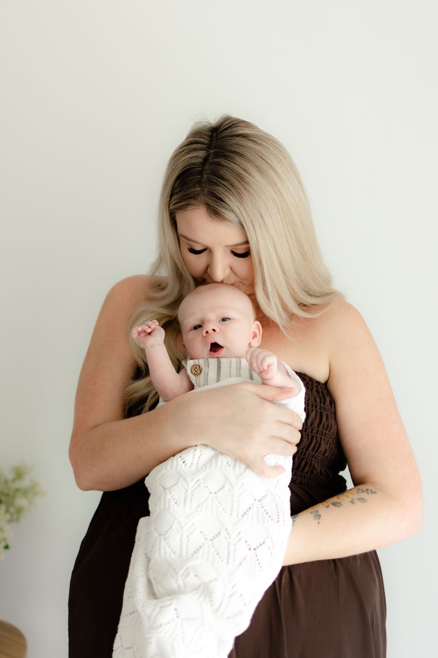 A series of tender moments between a parent in black holding and embracing a baby wearing white clothing.