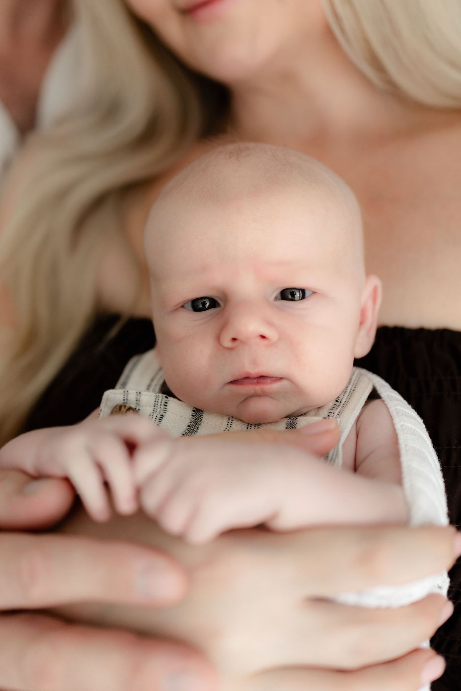 Close up of an alert baby with bright eyes being held securely by caring hands.