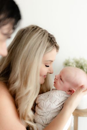 Intimate close-up shots of parent and baby sharing gentle moments against a bright background.