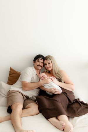 Family lying together on bed sharing intimate bonding moments with their newborn.