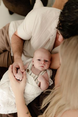 Series of tender moments between parents and infant wearing white clothing against light background.