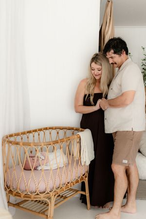 Progressive shots of couple arranging and preparing rattan baby crib in minimalist nursery.