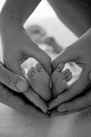 Black and white sequence showing gentle massage of baby's tiny feet.