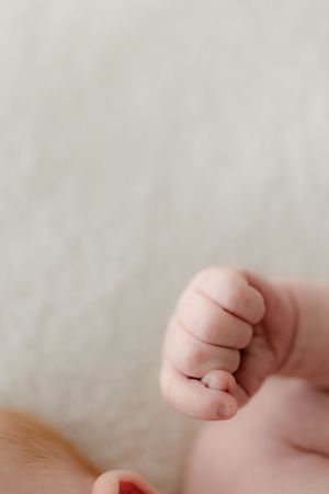 Close-up macro shot of tiny baby toes against a light cream background.