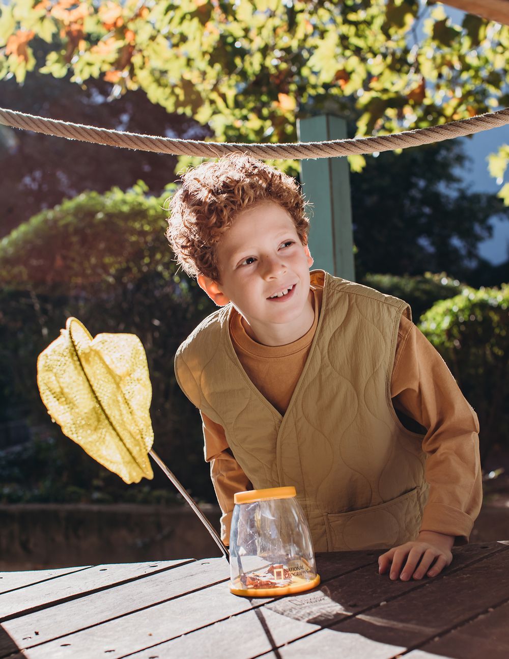 A series of photos showing someone experimenting with photographing a sandwich and glass on a wooden picnic table outdoors.