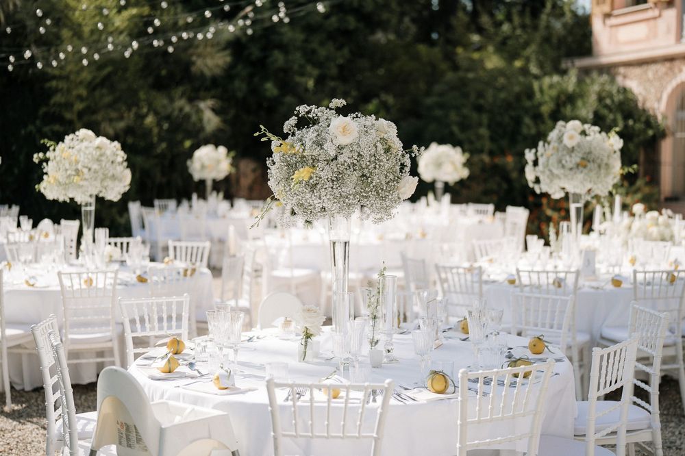 Allestimento del ricevimento di matrimonio nel giardino di Villa Nobel a Sanremo con tavoli rotondi e centrotavola floreali