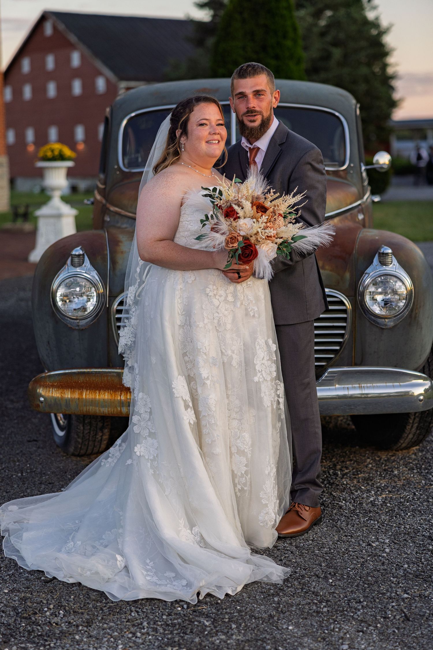 frederick maryland wedding photographer Wedding couple poses with vintage car at sunset in front of brick building.