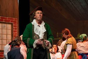 theatre photography Brighton actor stands on stage dressed a captain hook with the cast in the background