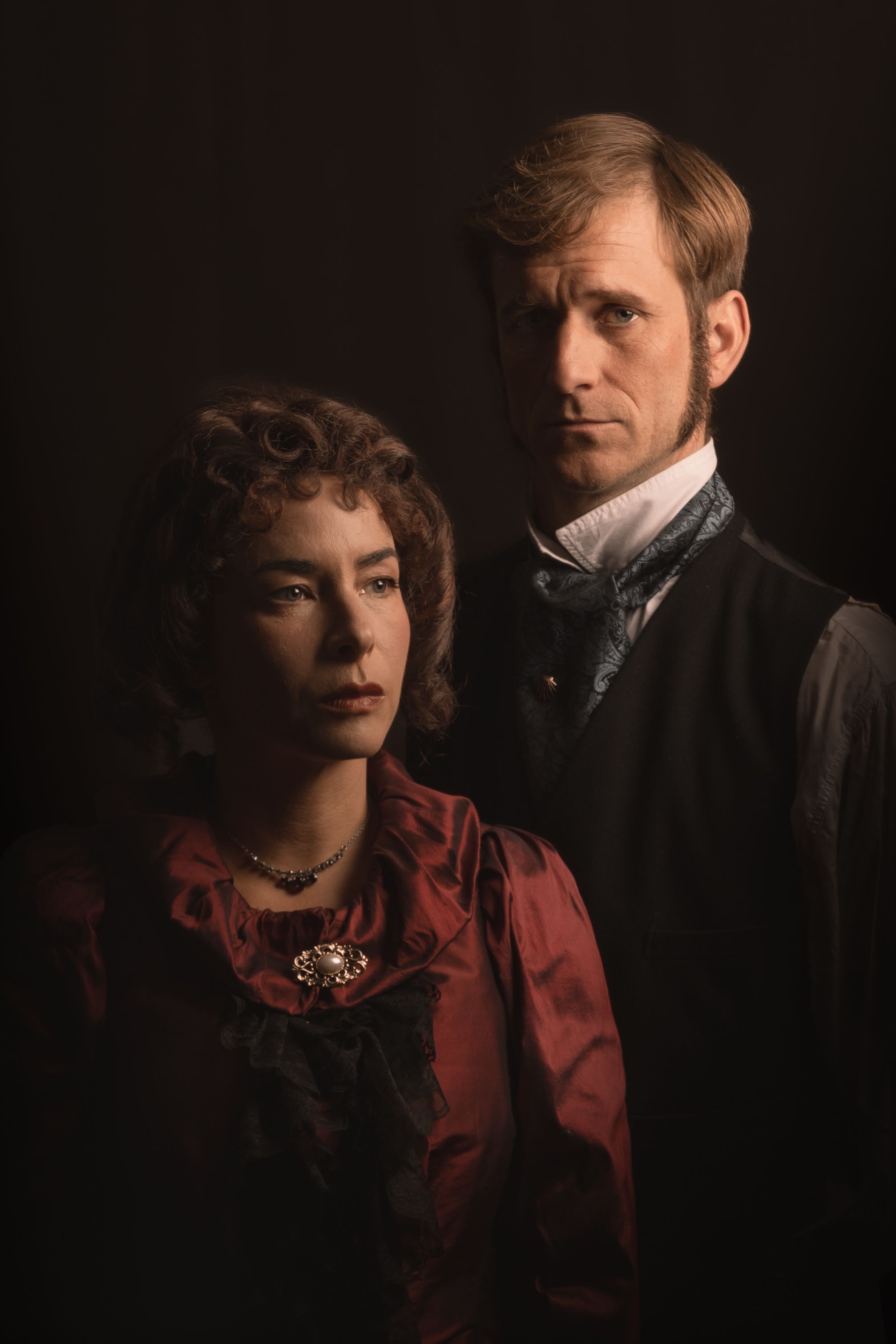 two actors stand in dimly lit scene wearing victorian costumes for a promotional shoot for great expectations. Brighton