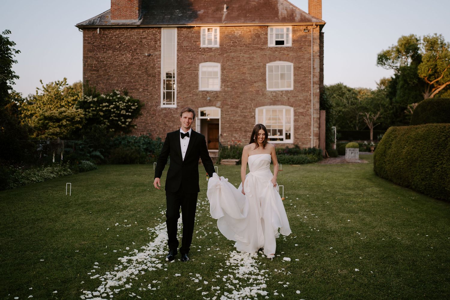 bride and groom walking across lawn at dewsall court in herefordshire