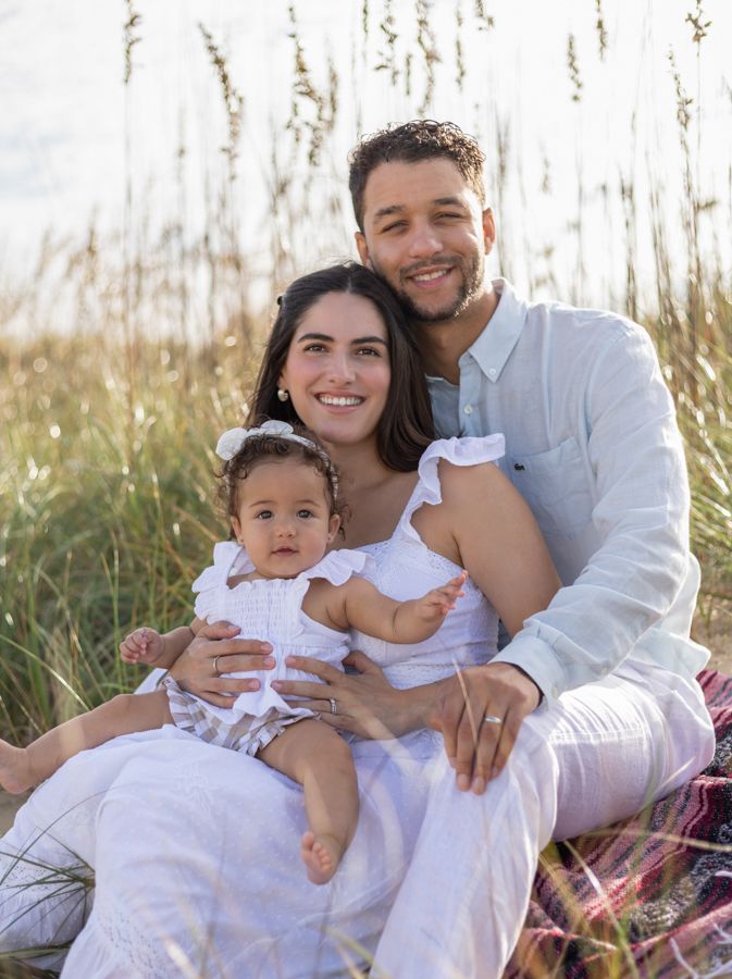 mom and dad holding daughter on virginia beach oceanfront in the beach grass