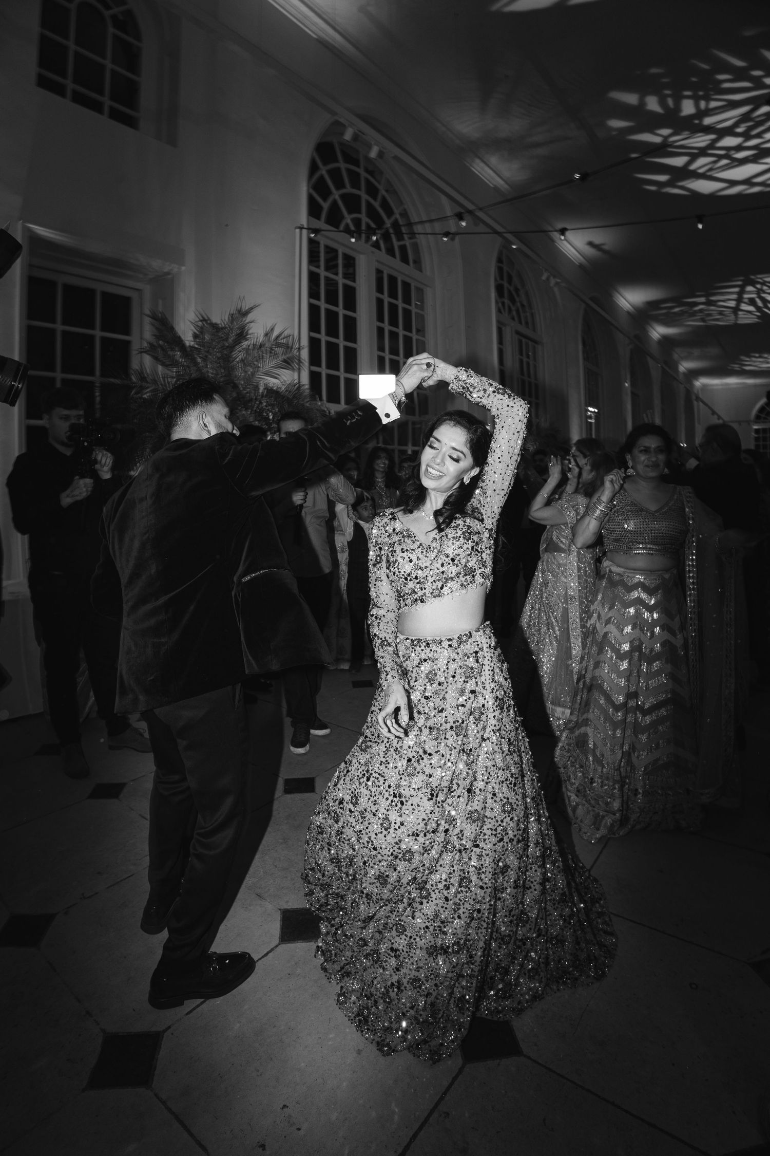 Atmospheric black and white documentary shot of an Indian couple dancing in the Kew Gardens Orangery under dramatic lighting