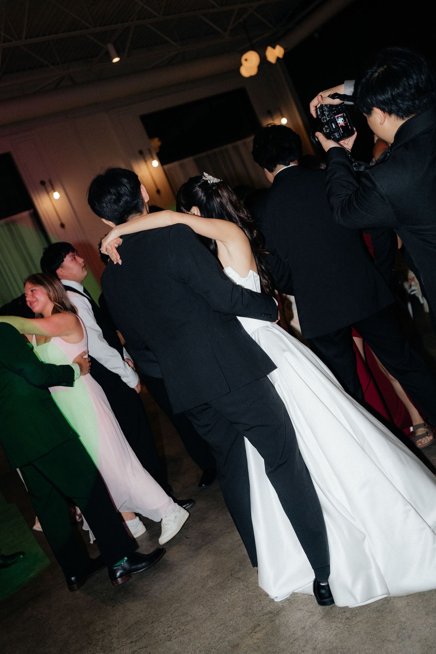Couples dancing together during a dimly lit wedding reception.