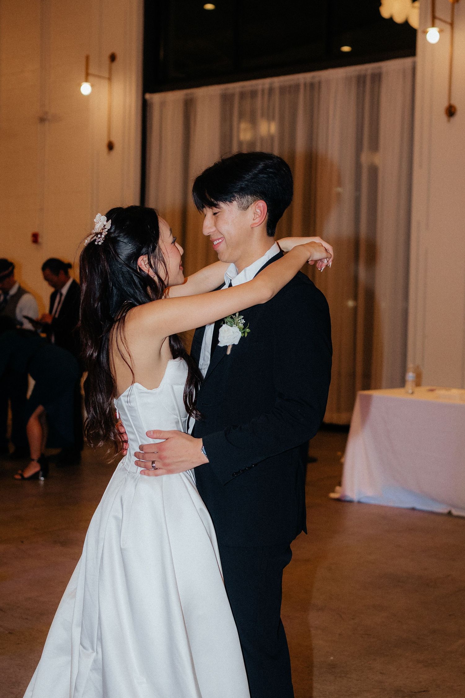Couple sharing a romantic dance together in formal attire at an elegant indoor venue.
