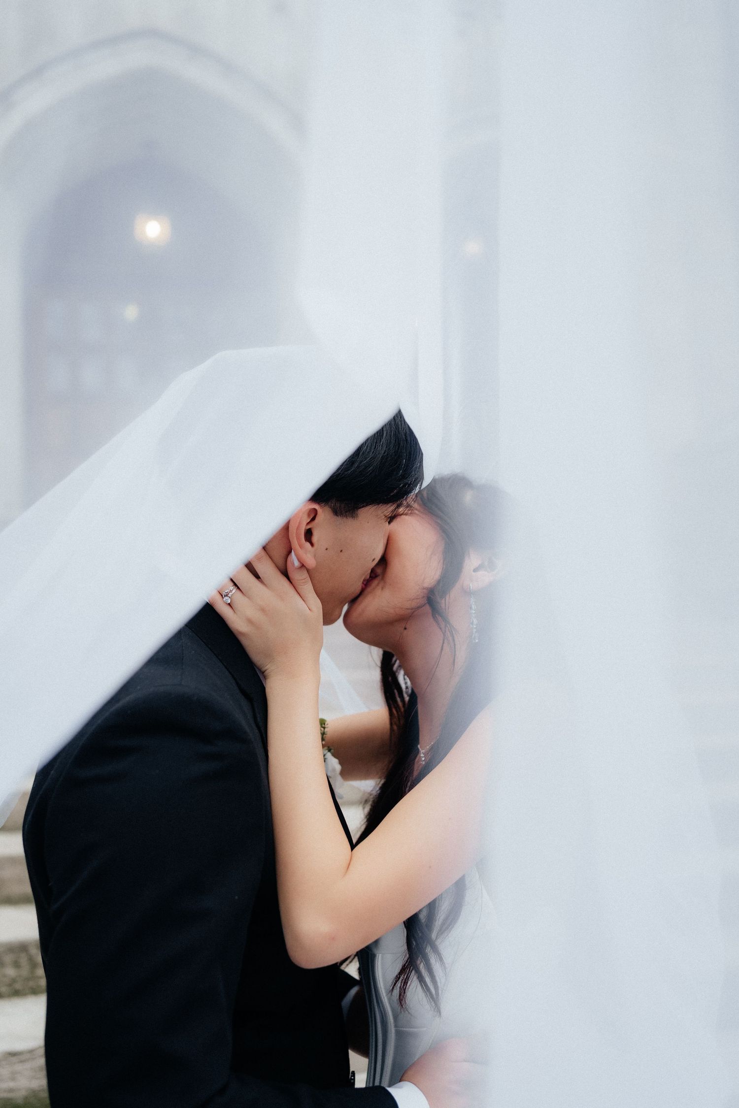 Romantic moment captured through flowing white veil during wedding photoshoot.