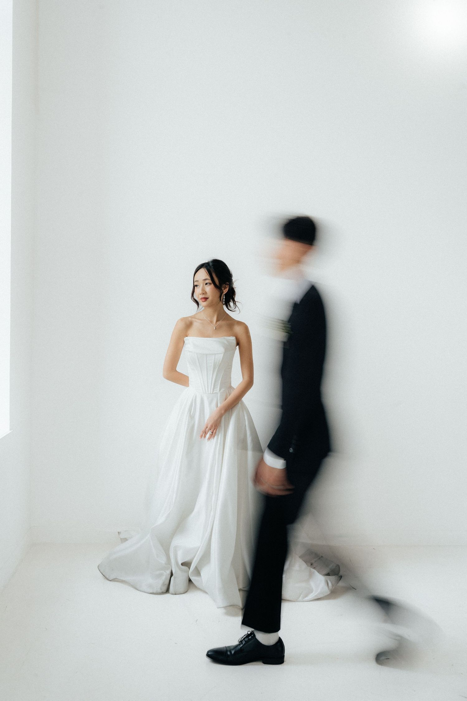 Artistic minimalist wedding portraits against white backdrop with motion blur effects.