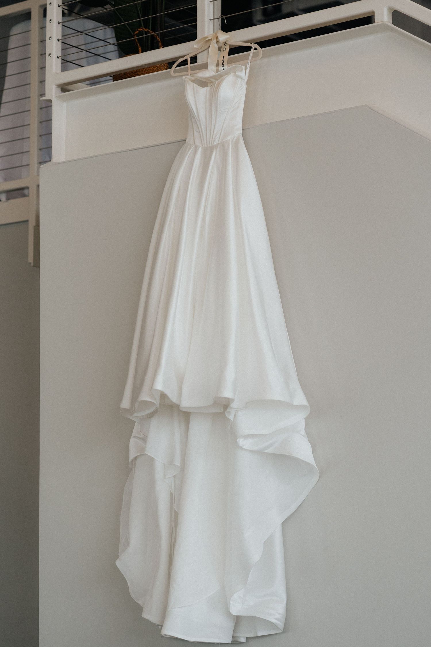White wedding dress hanging on display showing its elegant silhouette and flowing fabric details.