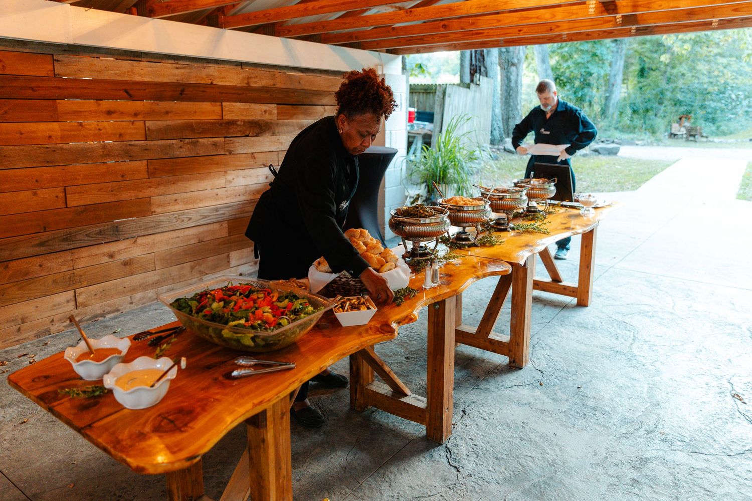 People dining at rustic wooden picnic tables under a covered outdoor patio area. live event photography st louis.