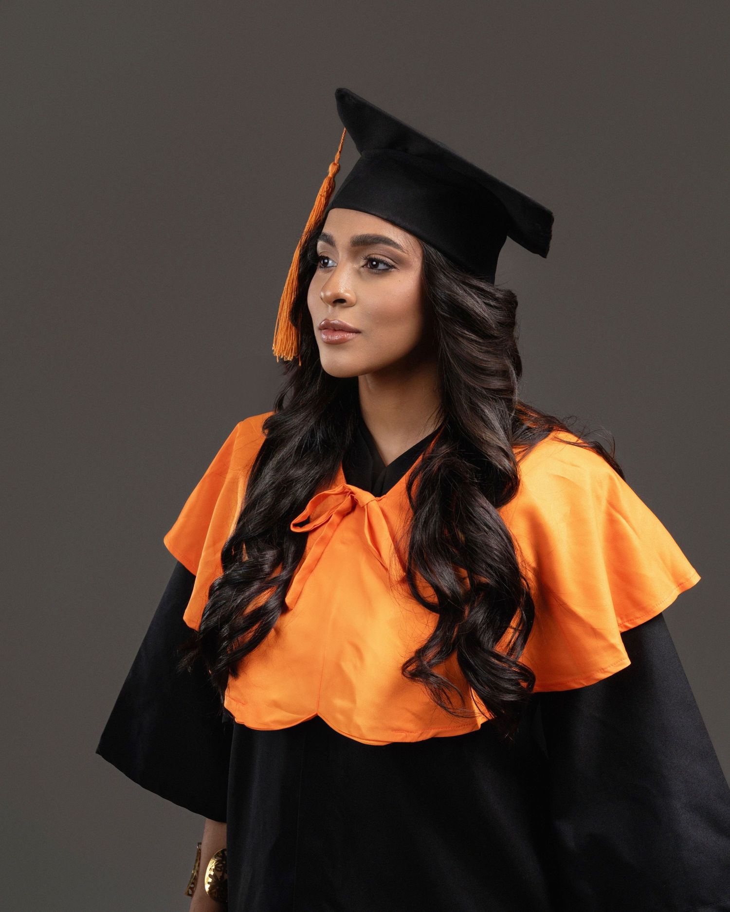 Graduate in cap and gown holds blue diploma folder in sequence of professional studio portraits against gray background.