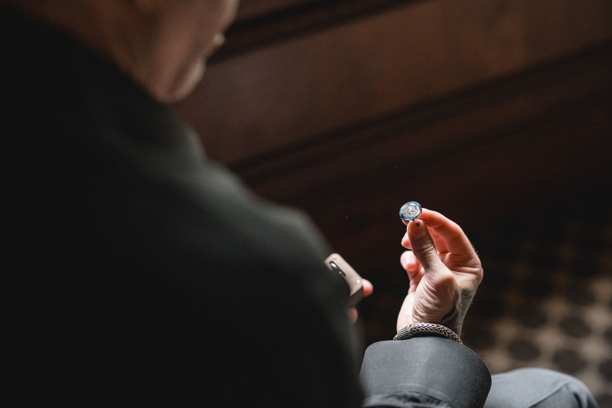 Close-up shot of hands holding and examining a wedding ring in soft lighting.