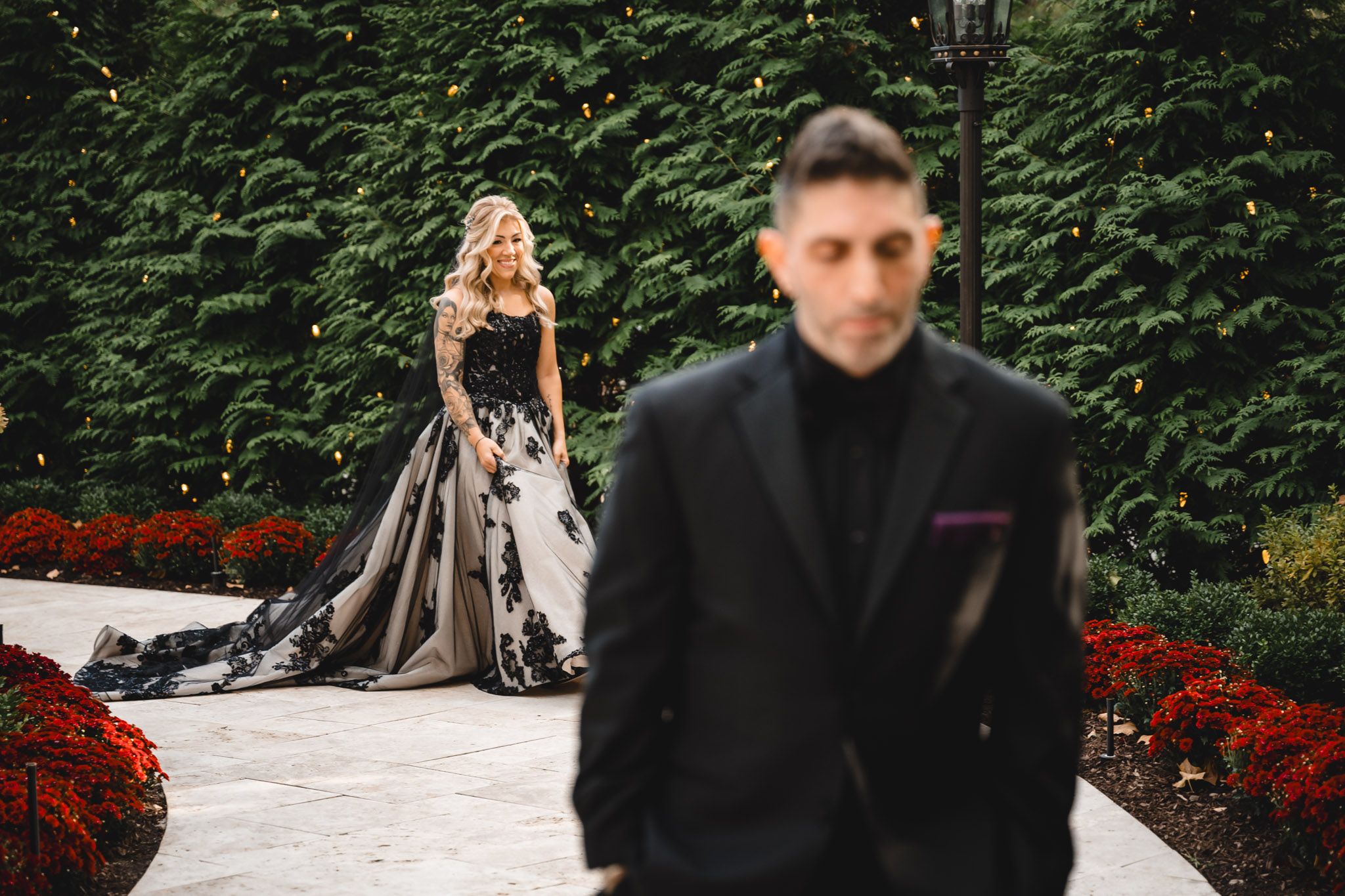 Romantic outdoor portrait session in a garden with red flowers and greenery.