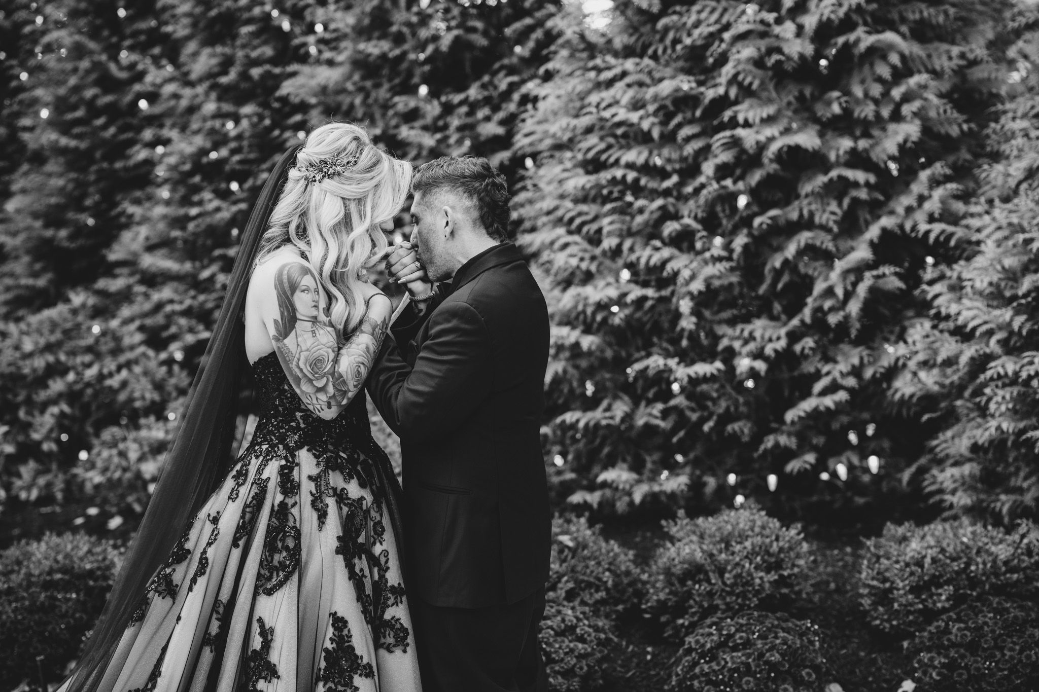 Couple sharing candid moments in front of lush garden backdrop.