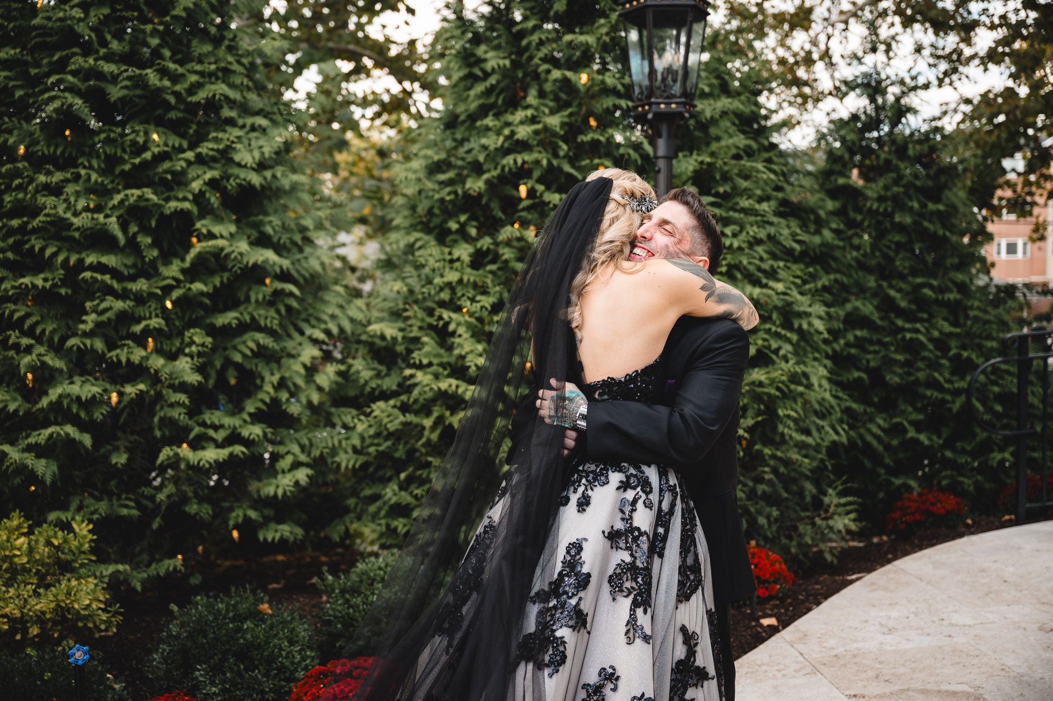 Couple dancing and twirling in formal wear against garden backdrop.