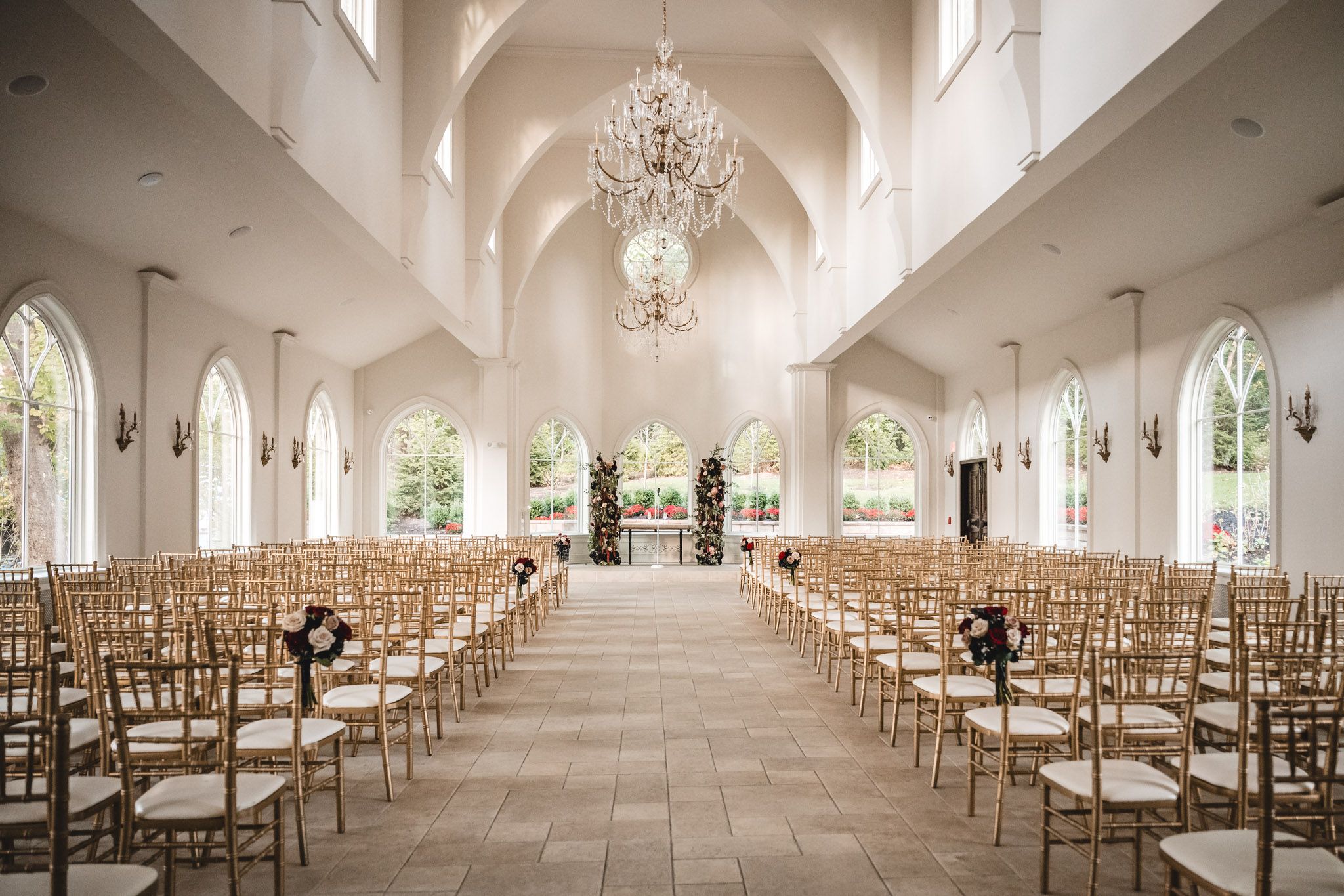 Elegant white chapel interior with crystal chandeliers and rows of gold chairs for ceremony.