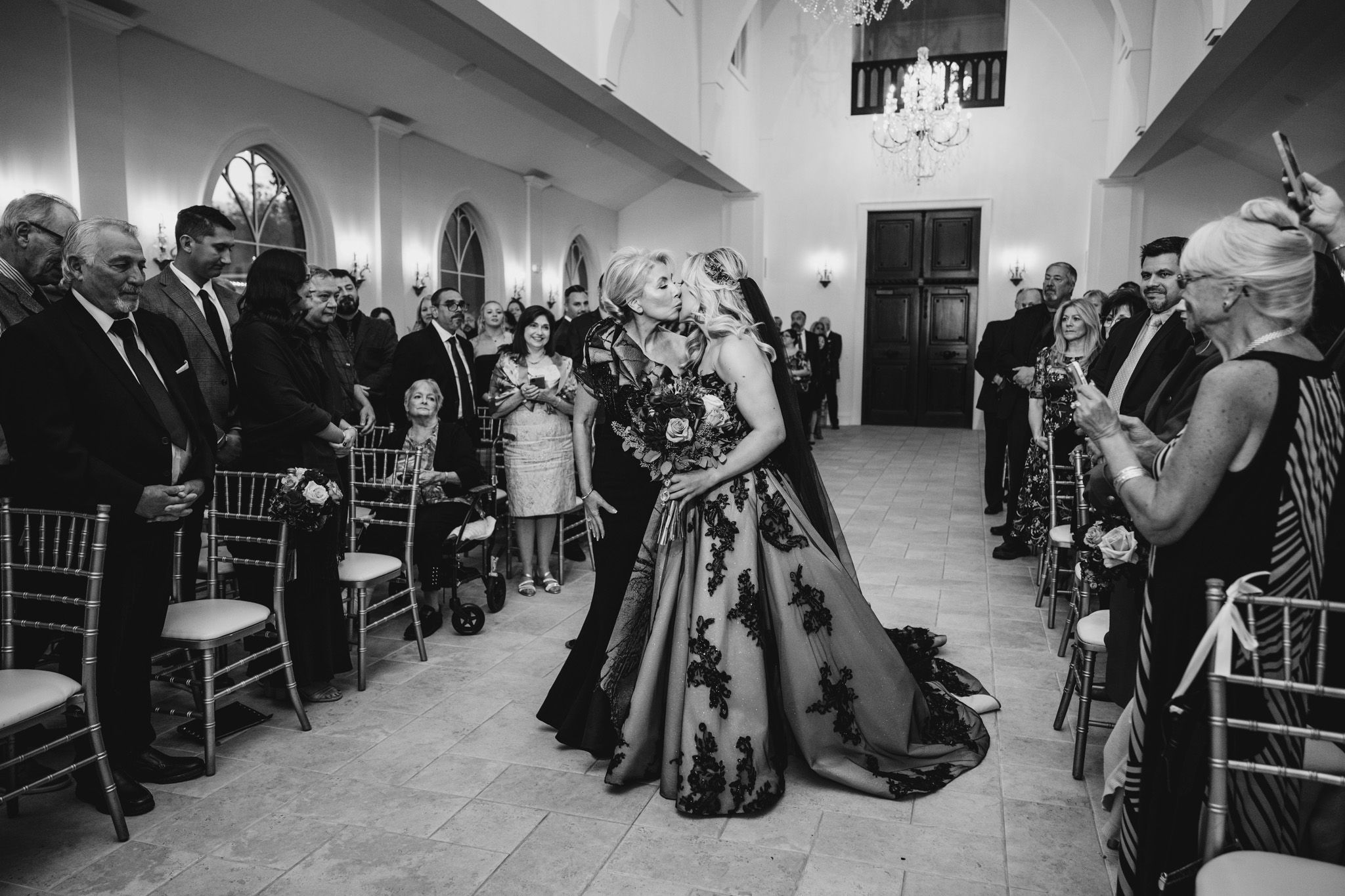 Wedding reception venue with guests seated at tables in a grand ballroom with vaulted ceilings.