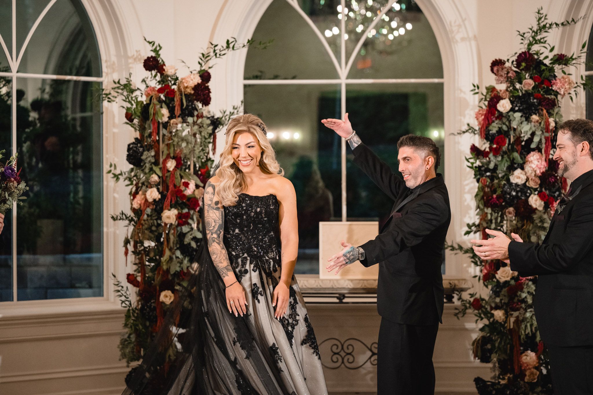 Elegant wedding ceremony space decorated with red floral arrangements and crystal chandeliers.