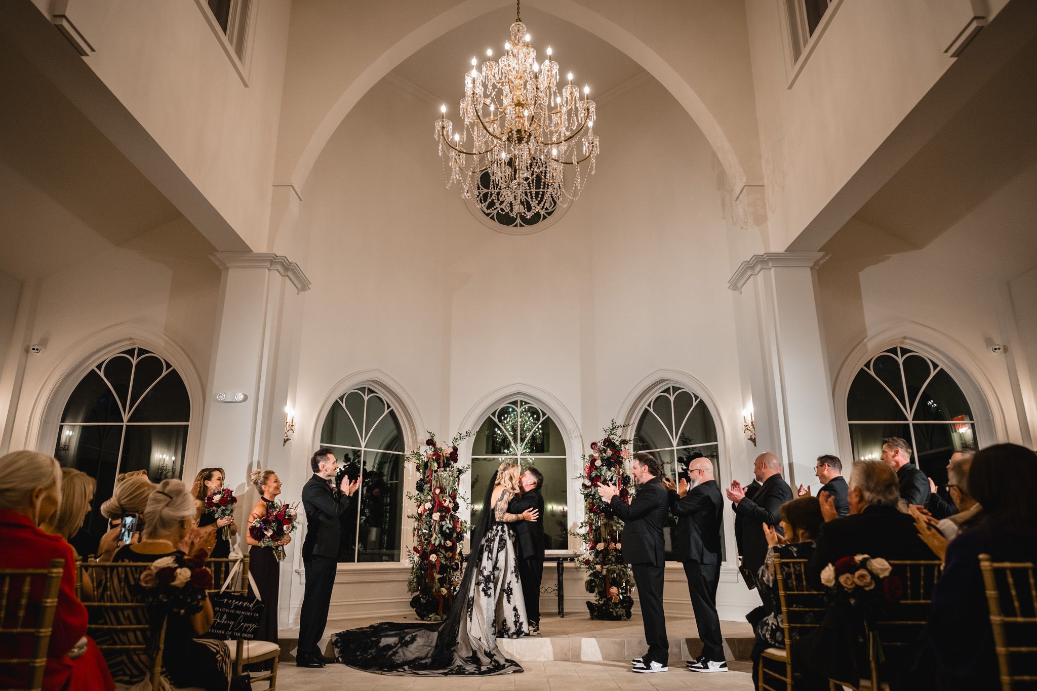 Panoramic view of an elegant wedding venue with crystal chandeliers and arched windows.