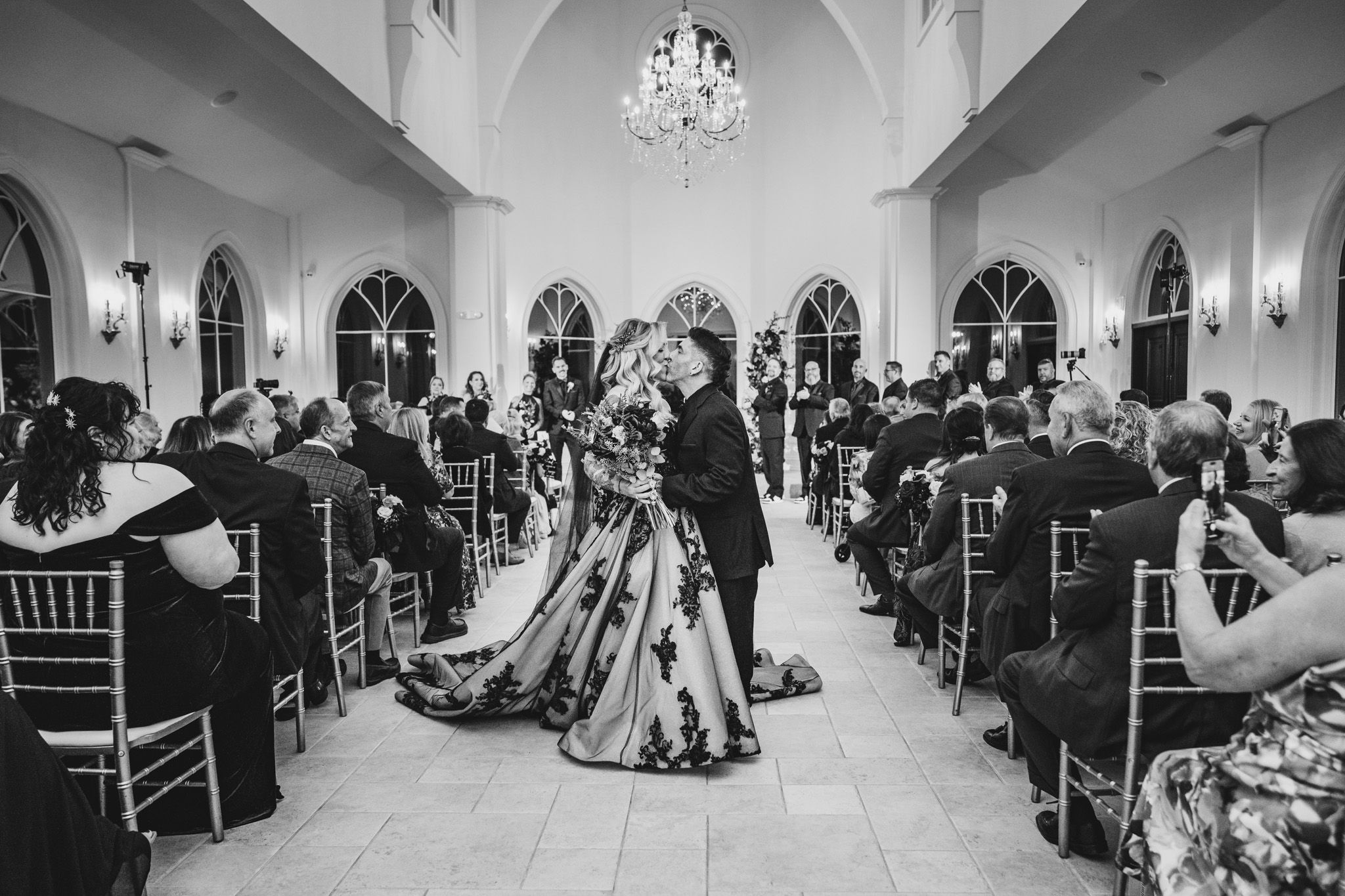 Wide-angle view of a wedding reception hall with classic architecture and crystal chandeliers.