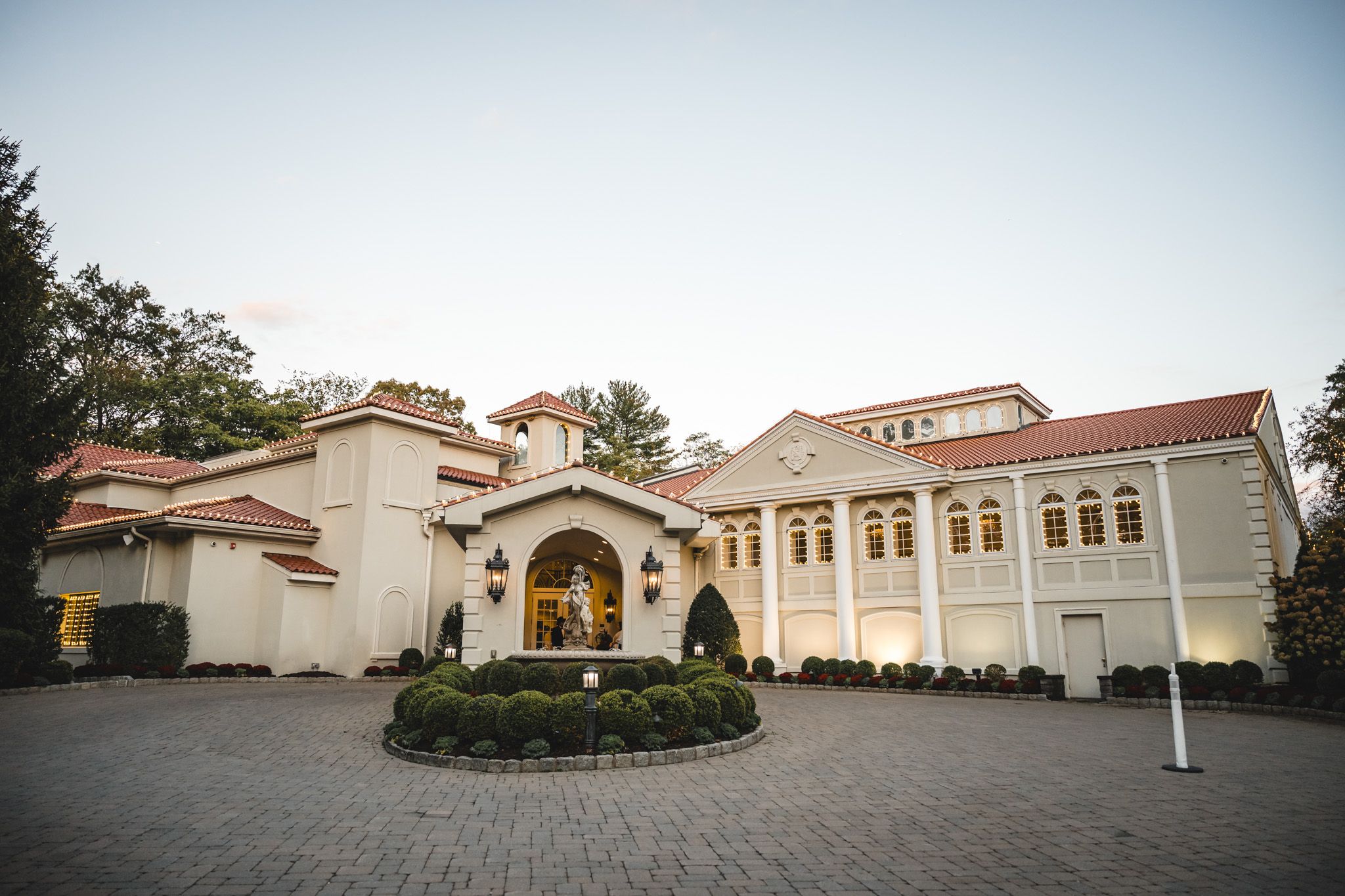 Panoramic exterior view of a Mediterranean-style wedding venue with terra cotta roof.