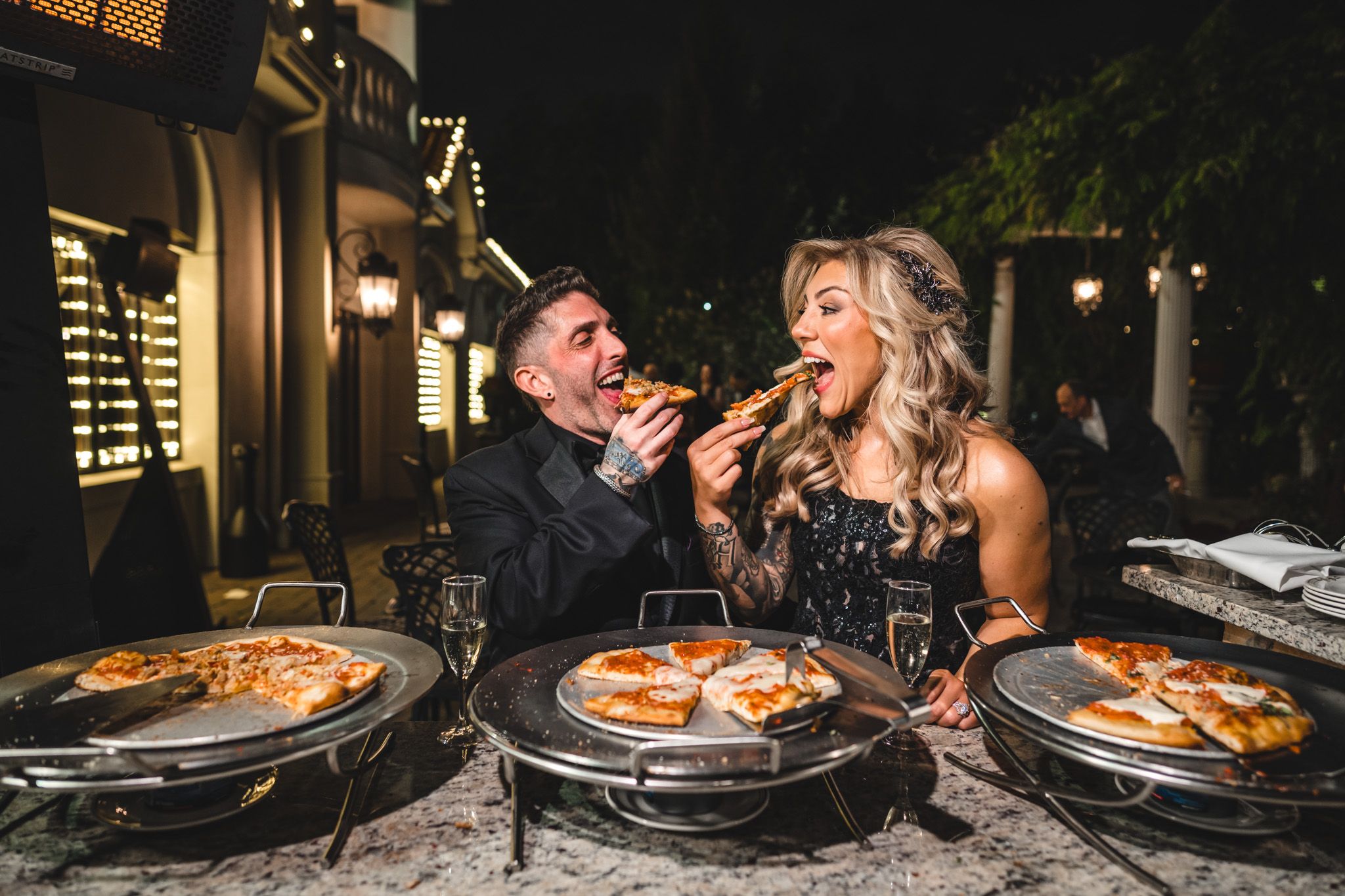 Guests enjoying pizza at an outdoor nighttime reception.