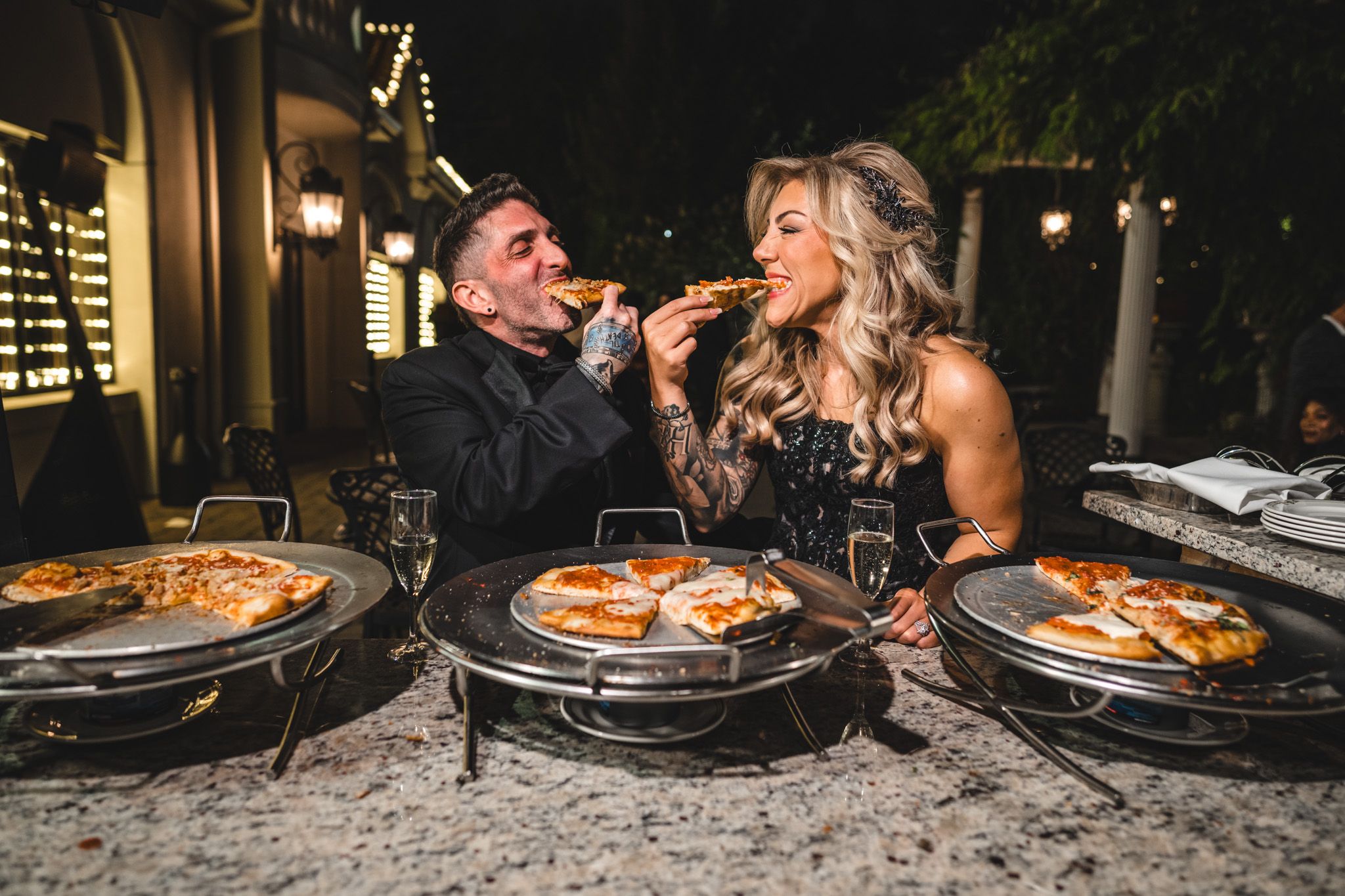 People sharing slices of pizza at a casual outdoor wedding reception.