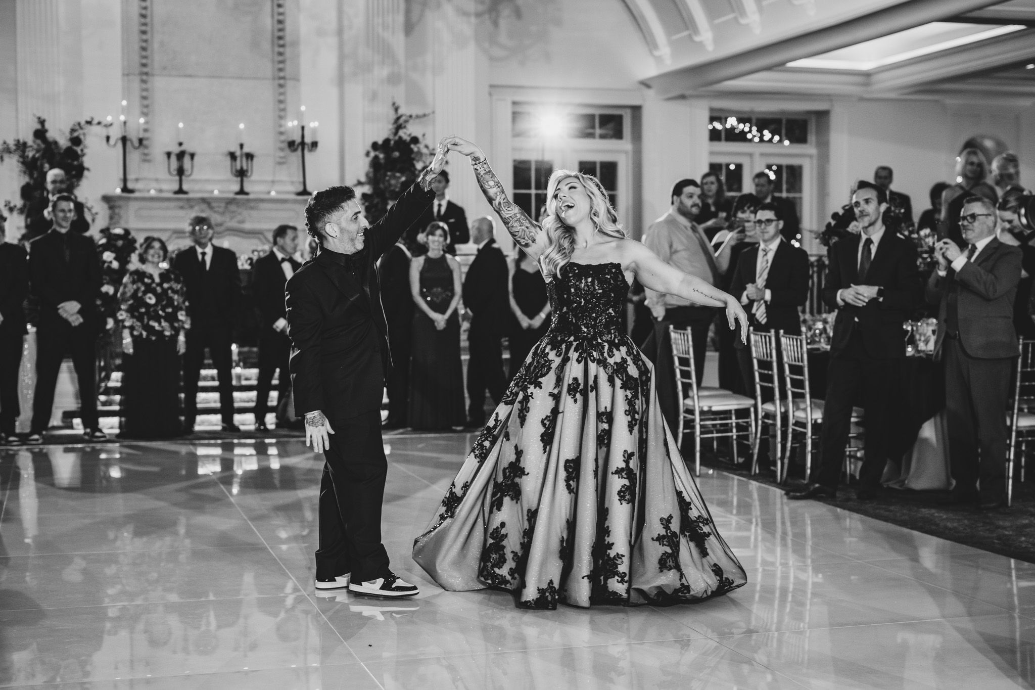 Wedding guests dance together in a ballroom with elegant chandeliers and decor.