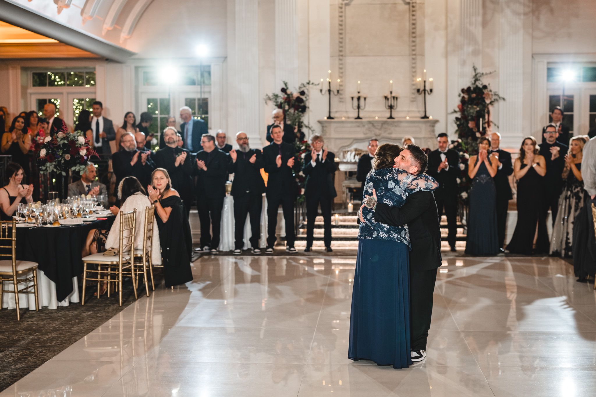 Elegant wedding reception venue with guests dancing on a white marble floor.
