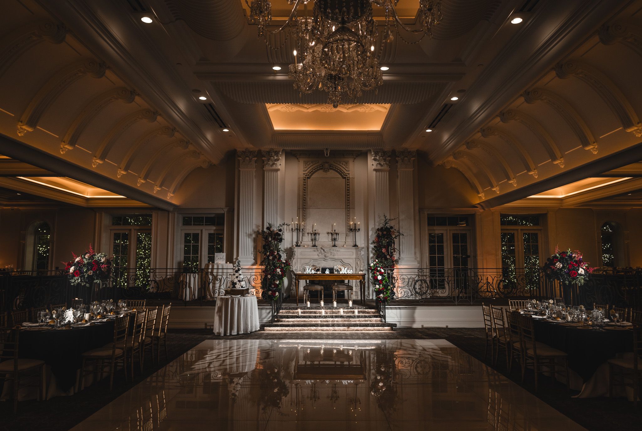 Panoramic view of an empty wedding reception ballroom with dramatic lighting and elegant decor.