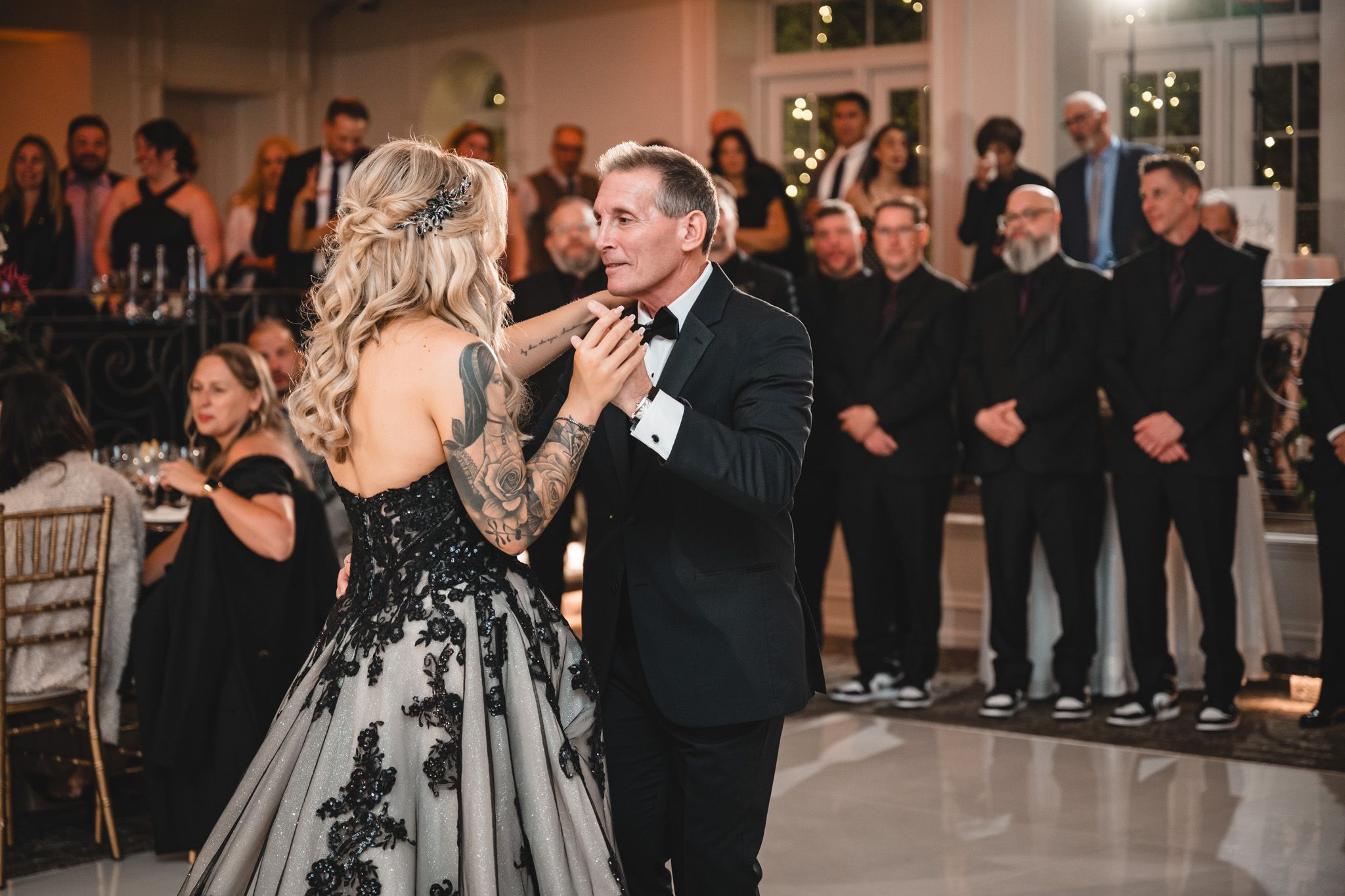Wedding party and guests celebrating on the dance floor during an evening reception.