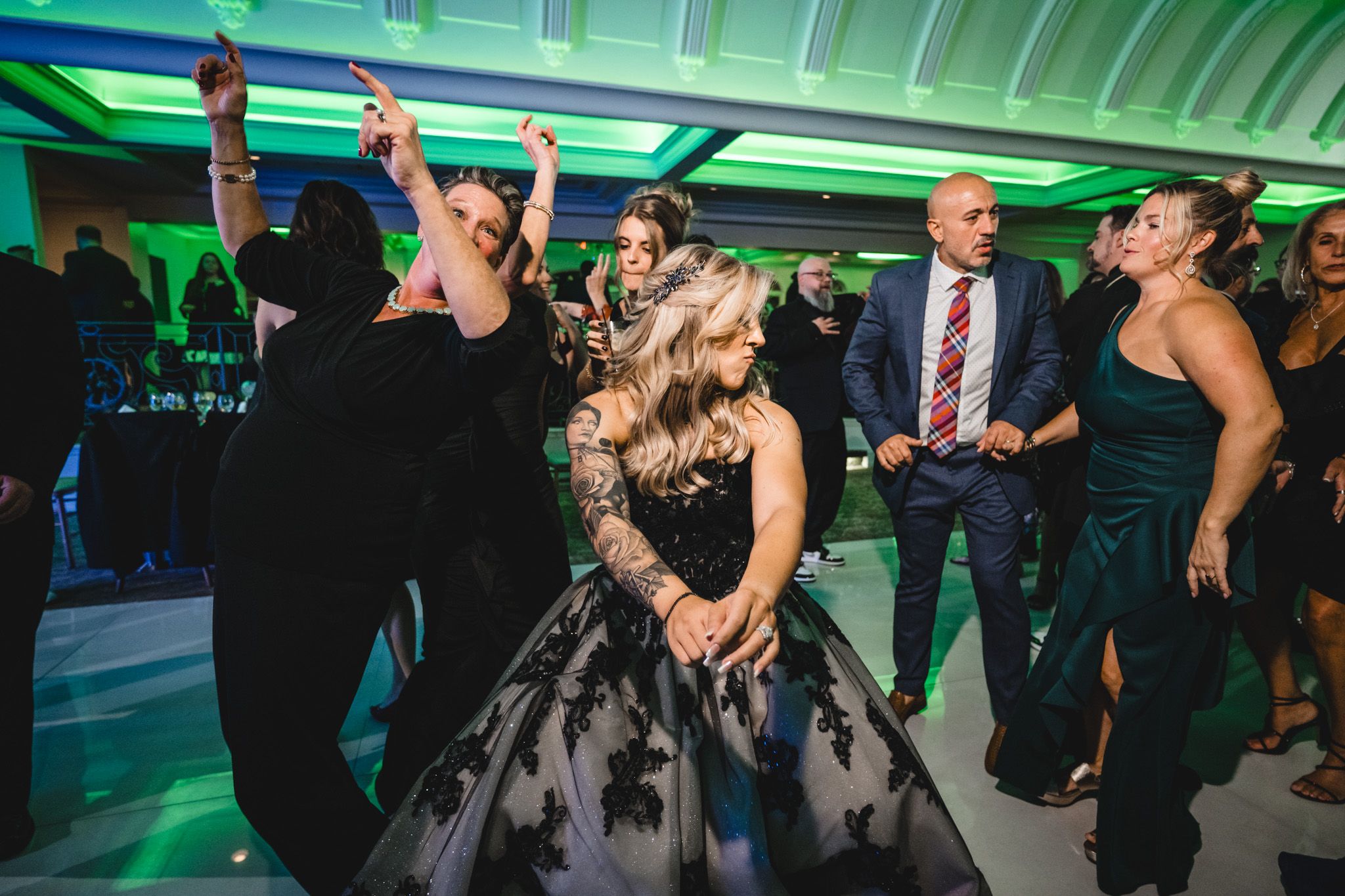 Wedding celebration with green ambient lighting and guests dancing.