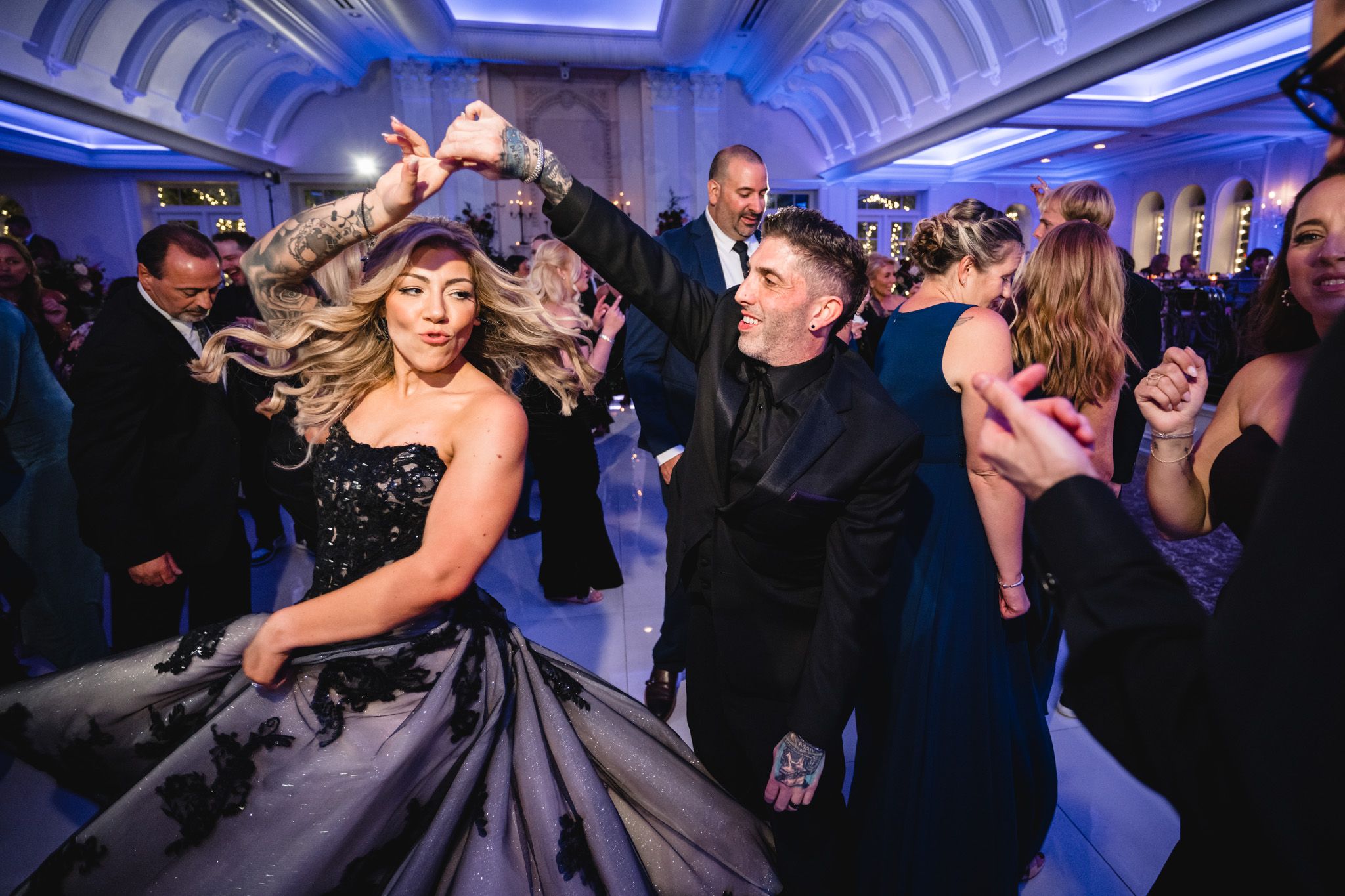 Wedding reception dance floor with dramatic blue lighting and vaulted ceiling.
