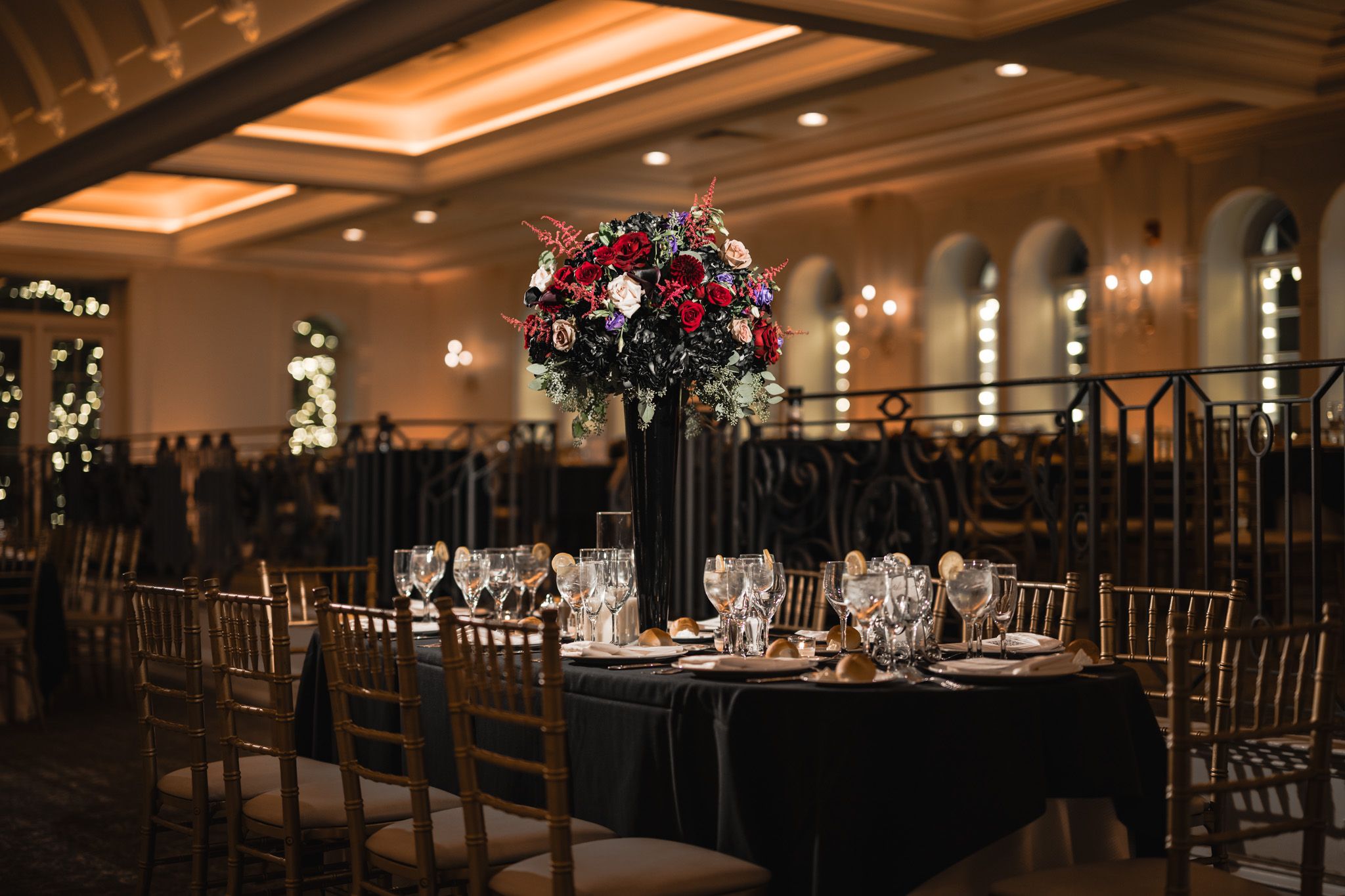 Elegant ballroom setup with dark tables and chairs for a formal reception.