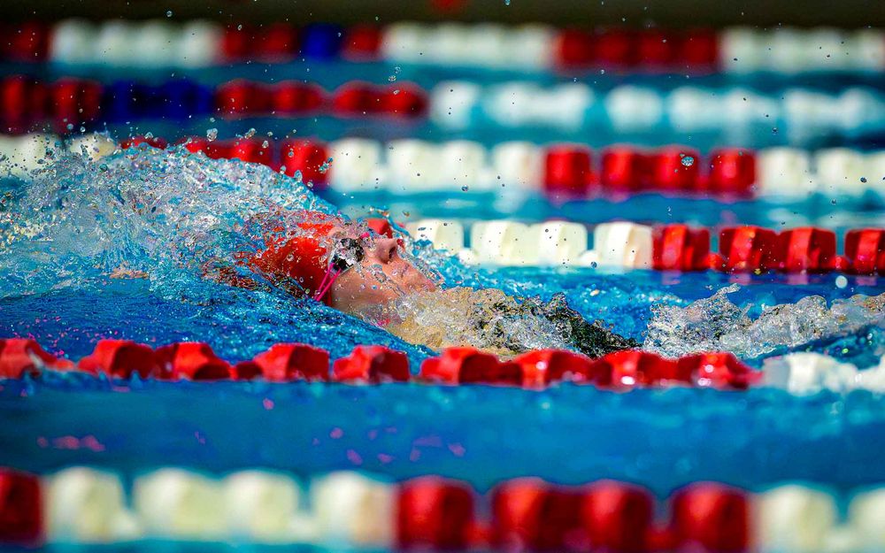 Cumberland Valley swimmer in red cap gliding underwater during a race at the Keystone meet against Hershey.